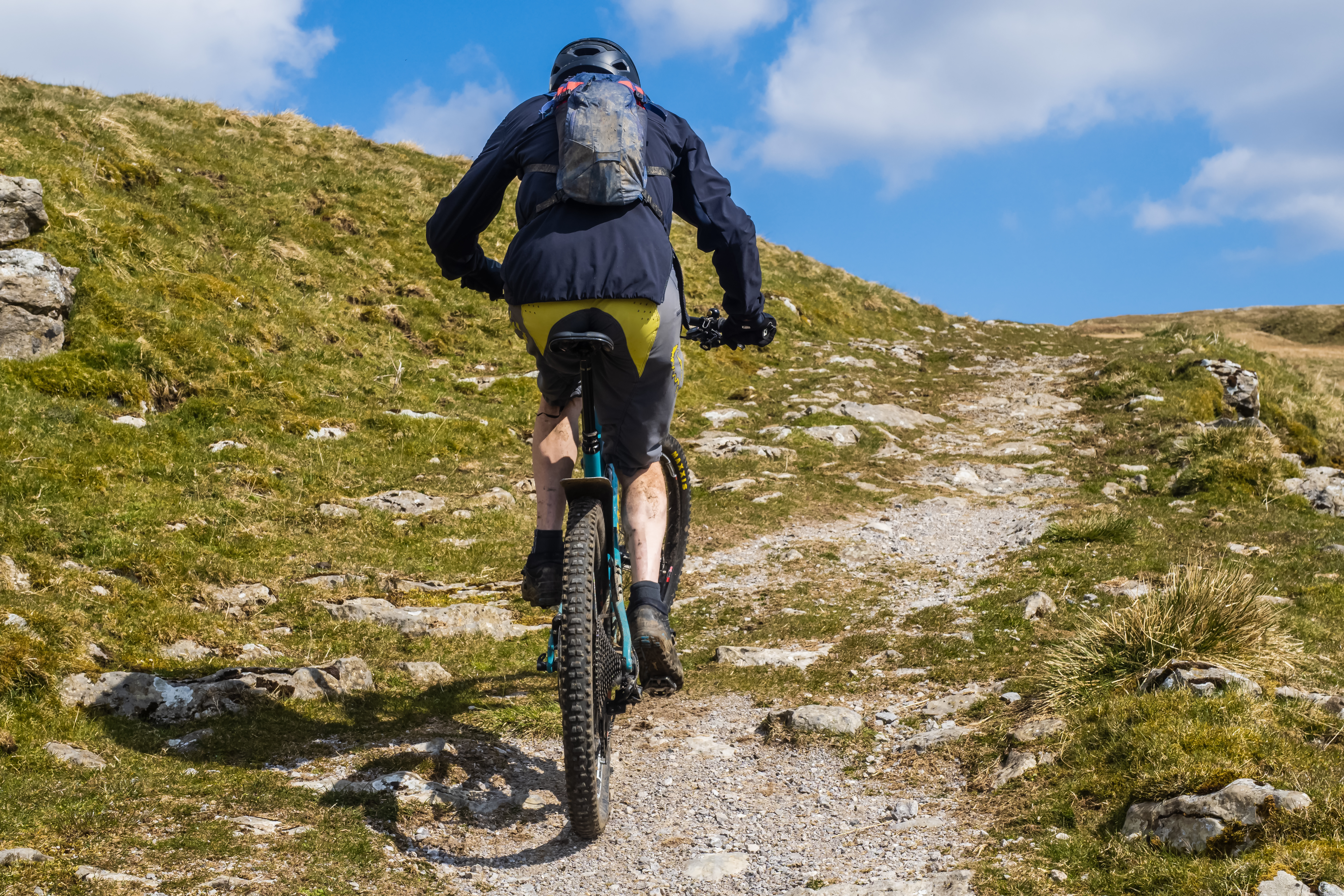 rear view of a mountain biker scaling a chalky footpath on a hillside in Yochenthwaite, yorkshire dales