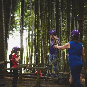young children being encouraged to tackle the low ropes course