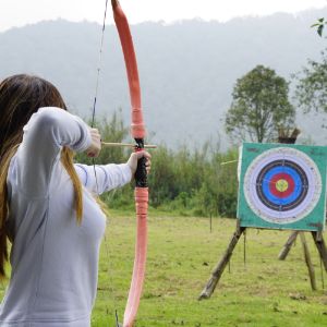 female poised to fire a bow at an archery target