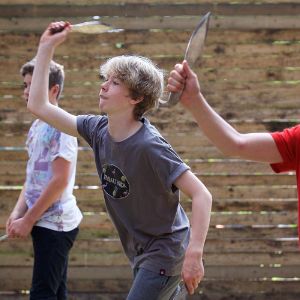 Three youths preparing to thorw axes at a target