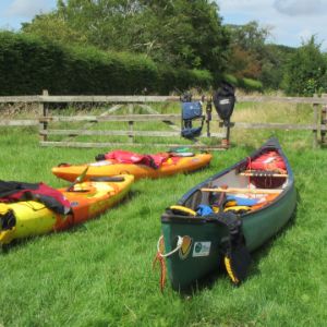 canoe and tw kayaks on grass
