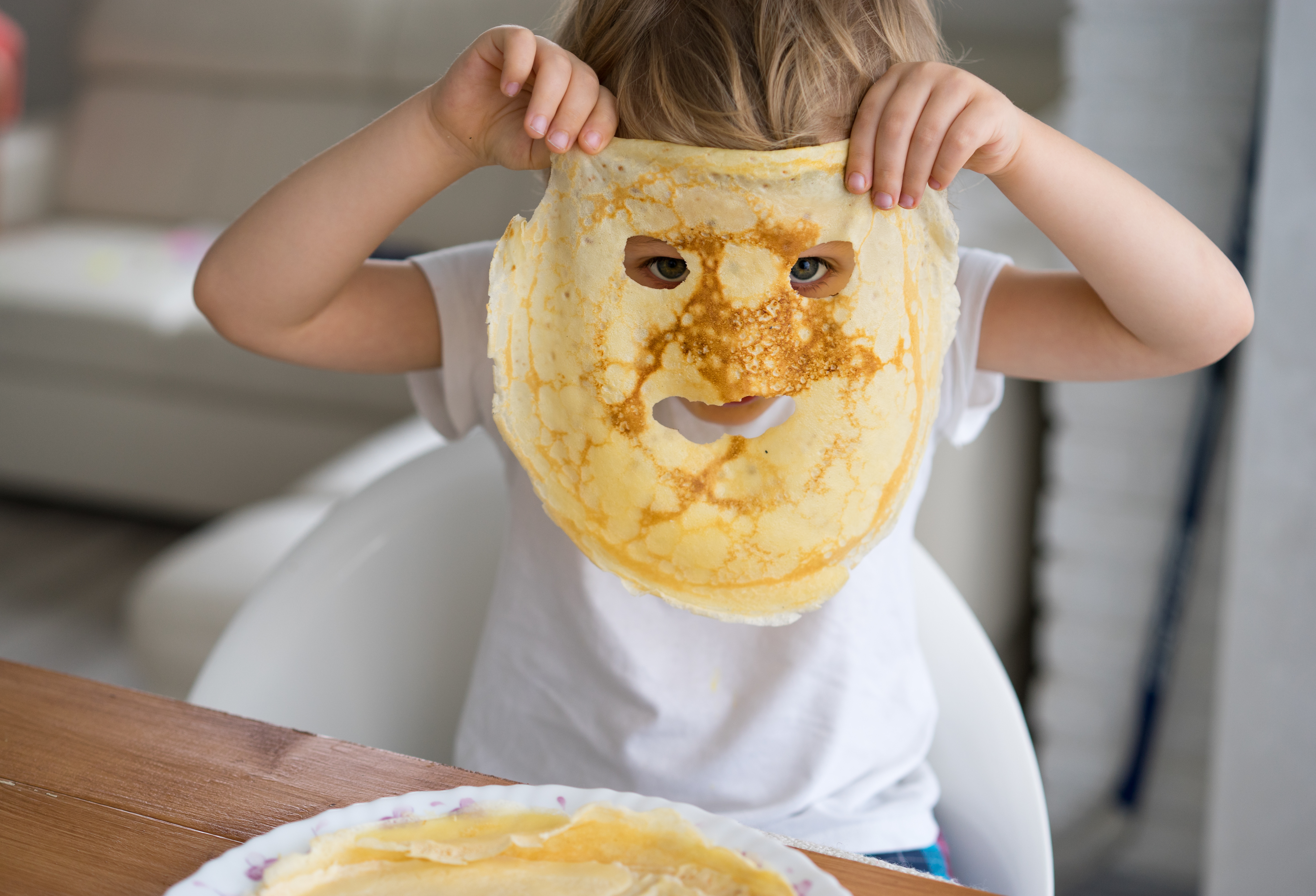 Small boy holding smailey face pancake in his own face