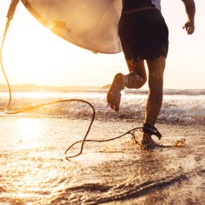 surfer running towards the sea with their board