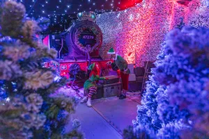 Train covered in Christmas decorations in a snowy scene.