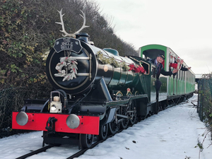 The Jungle Belle Train with driver and santa waving to the camera, on a snowy day.