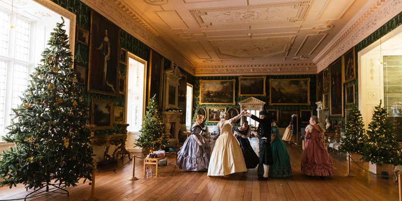 people in period dress dancing in one of the grand rooms at Temple Newsam stately home.