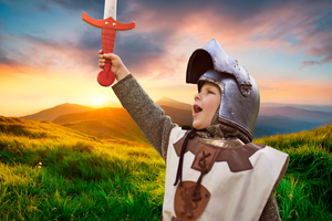 Boy dressed as a knight with wooden sword held aloft