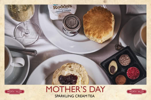 view of scones on a plate, one with jam and cream, one whole and a small tray of handmade chocolates.
