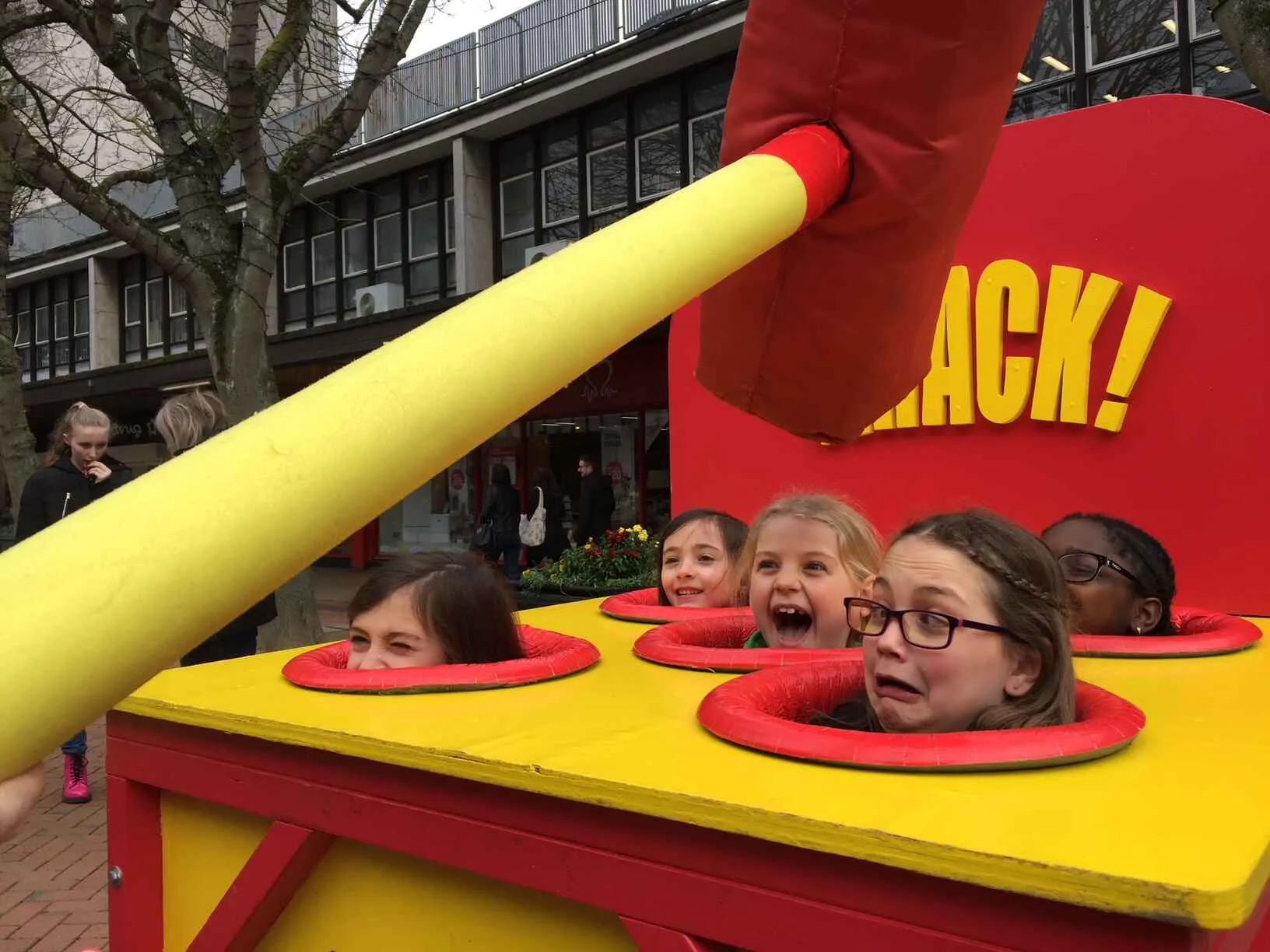 human whack a mole with children as the mole and a large red foam hammer
