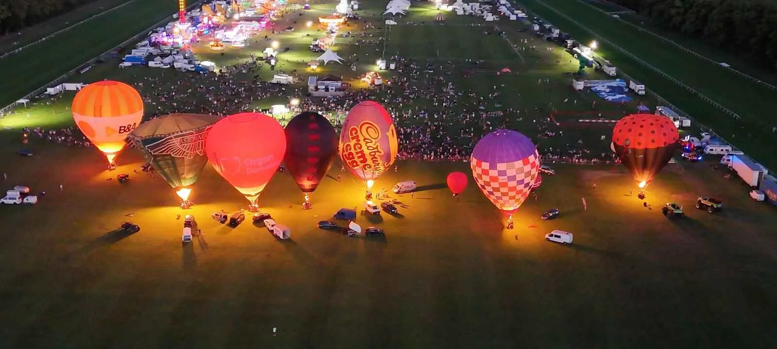 brightly coloured hot air balloon lit up and inflated at night