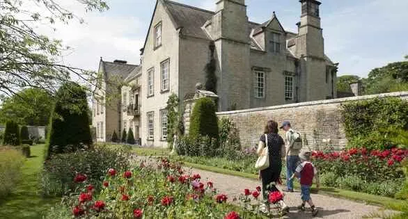 nunnington hall in the summer time with flower filled borders.