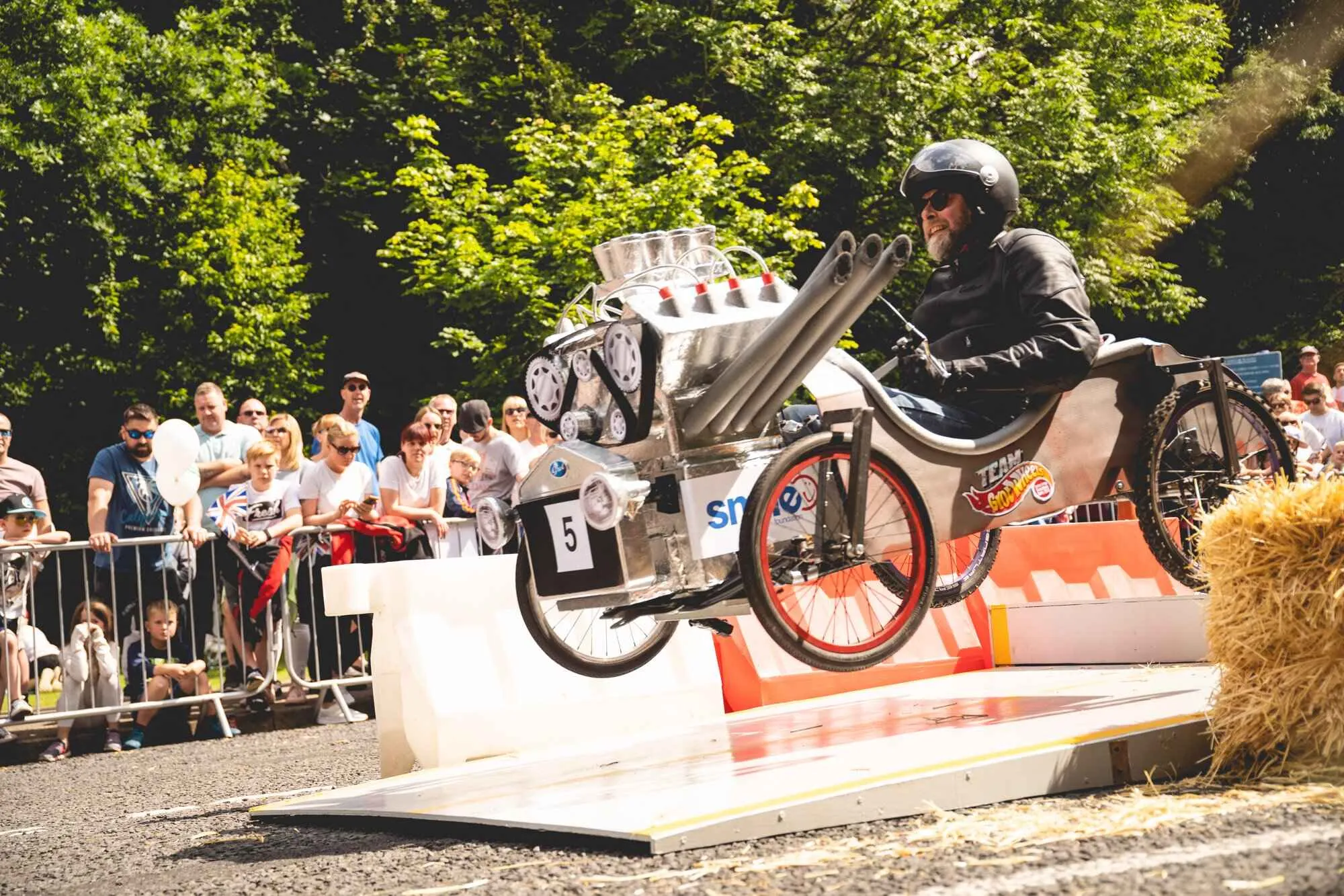man in a soapbox cart coming over a jump