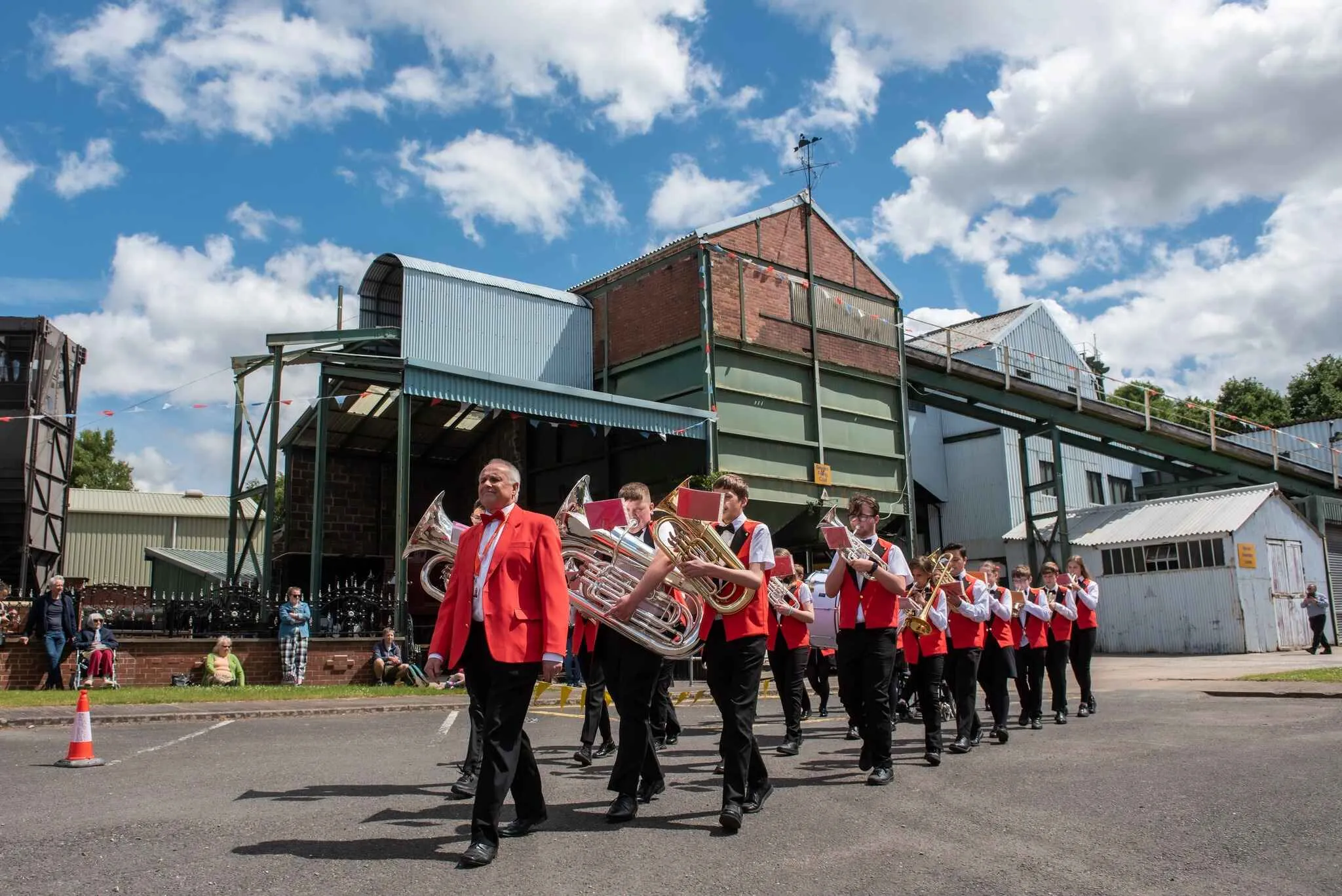 brass band marching through the National Coal Mining Museum with the pit head in the background
