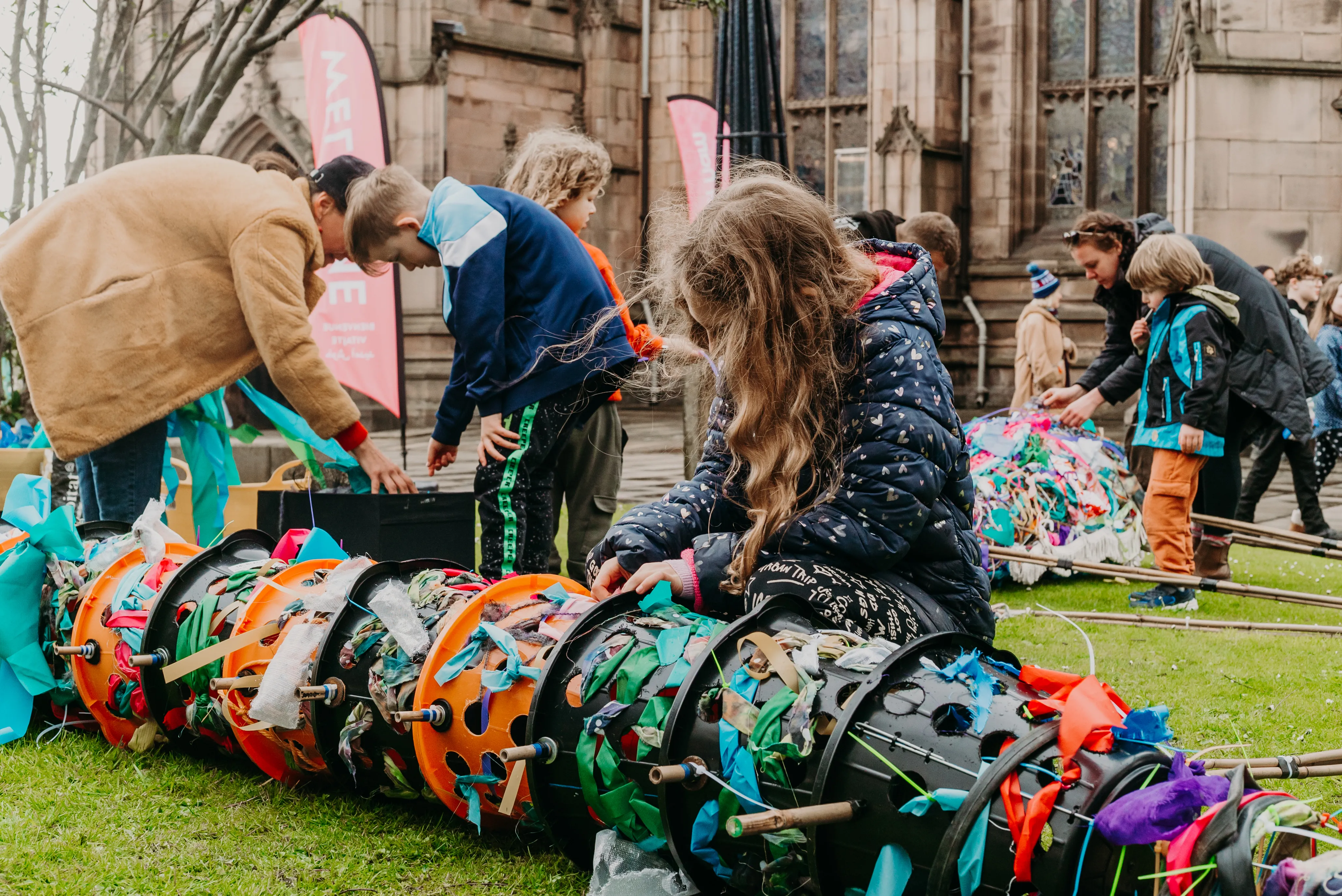 families building a puppet snake from buckets and brightly coloured streamers.