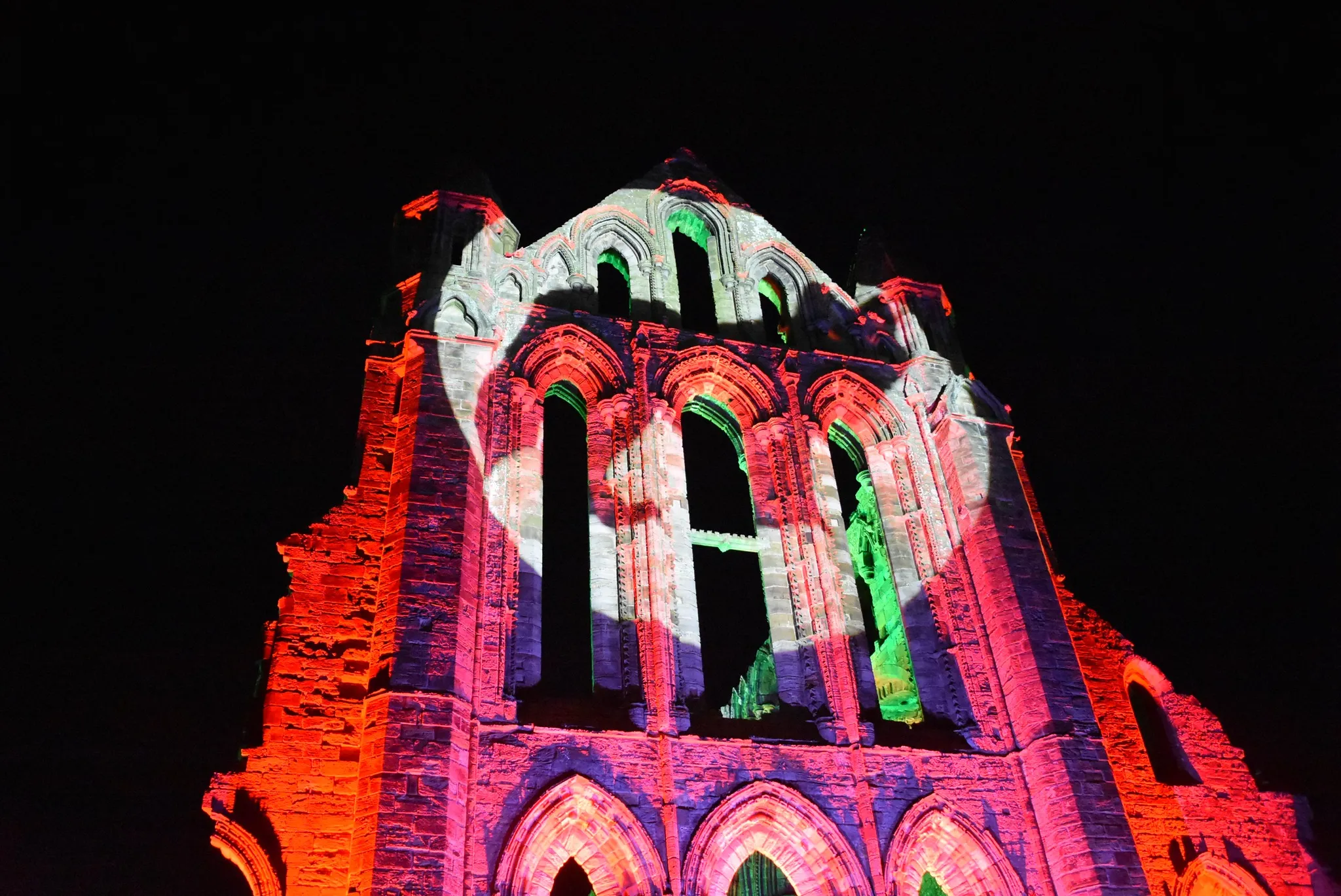 Whitby Abbet lit up in red with a wolf silhouette