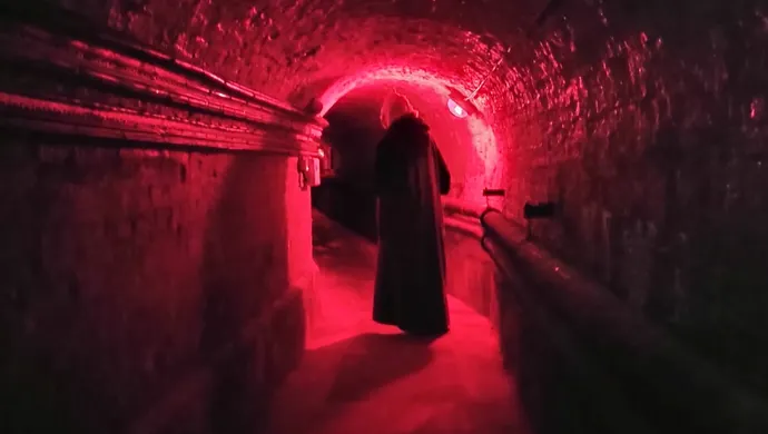 person walking through cellar corridors.