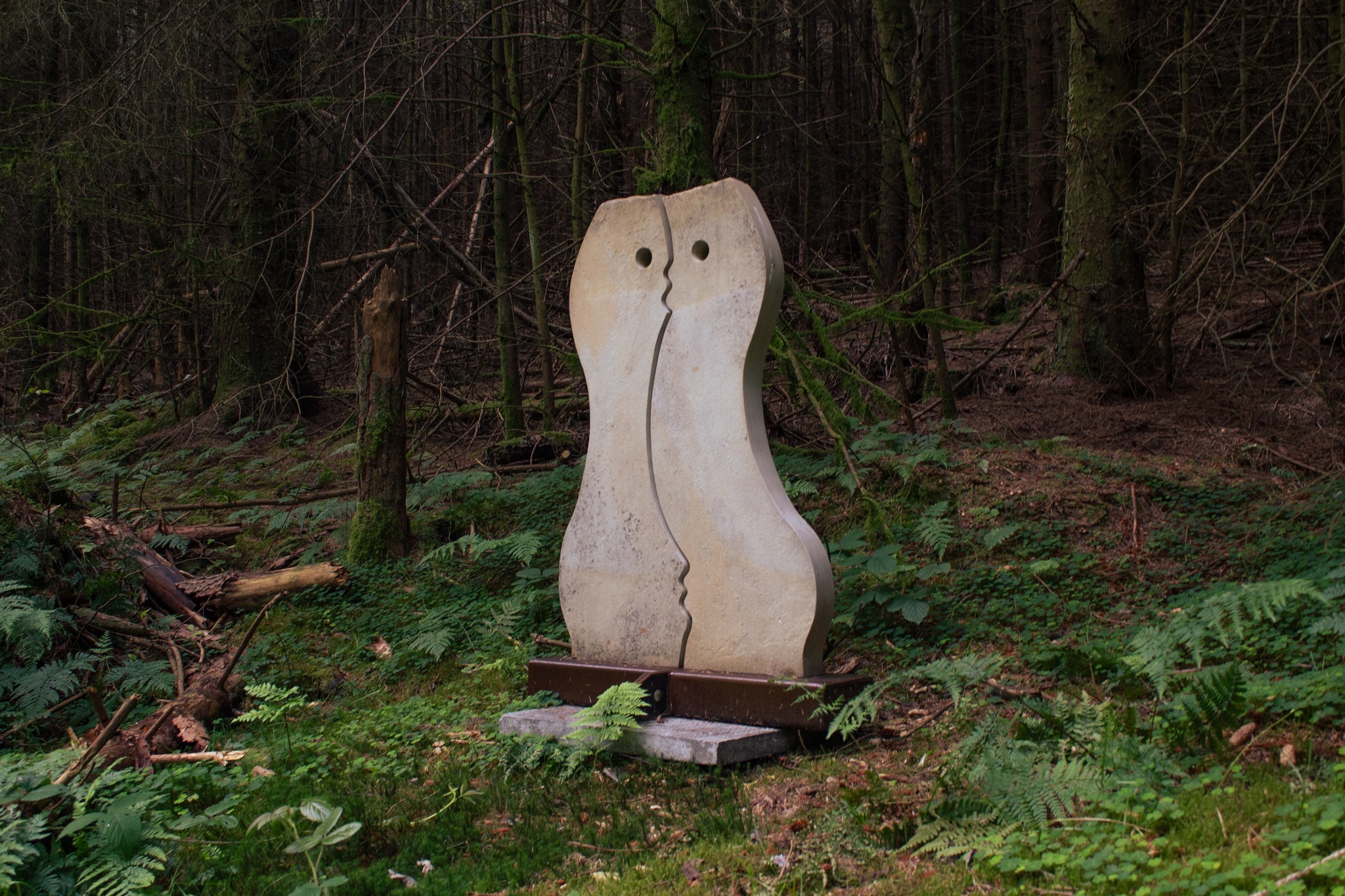 interlocking stone sculptures with trees of dalby forest in the background.