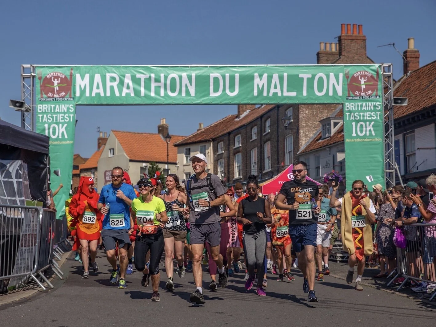 Runners in fancy dress under a malton 10k banner.